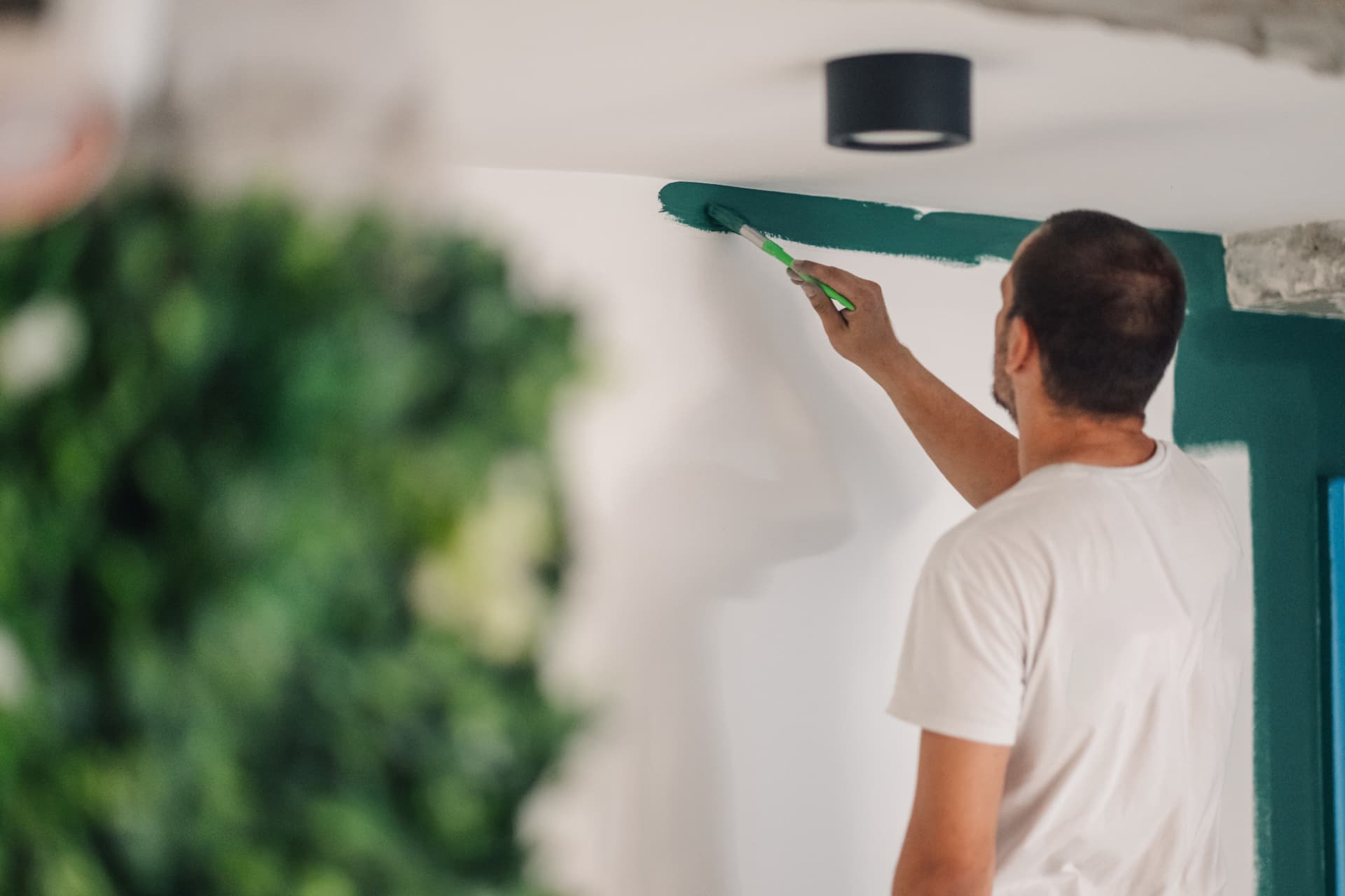 Painter cutting in a teal feature wall edge in a Newcastle home