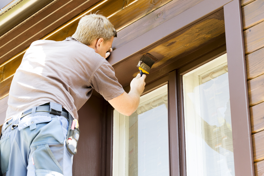 Painter brushing stain onto timber window trim on a Hunter Valley renovation