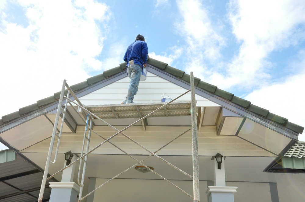 Painter on scaffolding repainting the gable and eaves of a Central Coast home during a renovation