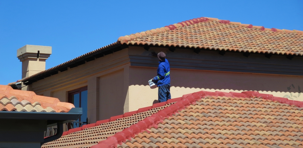 Painter working across a tiled roof on a Maitland residential exterior repaint