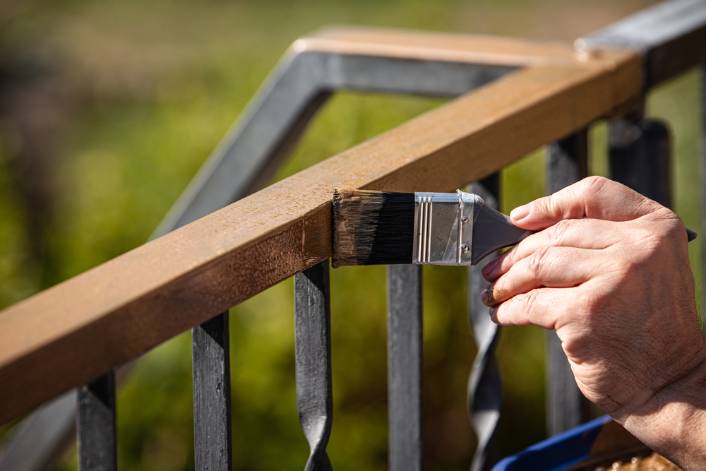 Painter brushing fresh stain onto a timber handrail on a Hunter Valley job