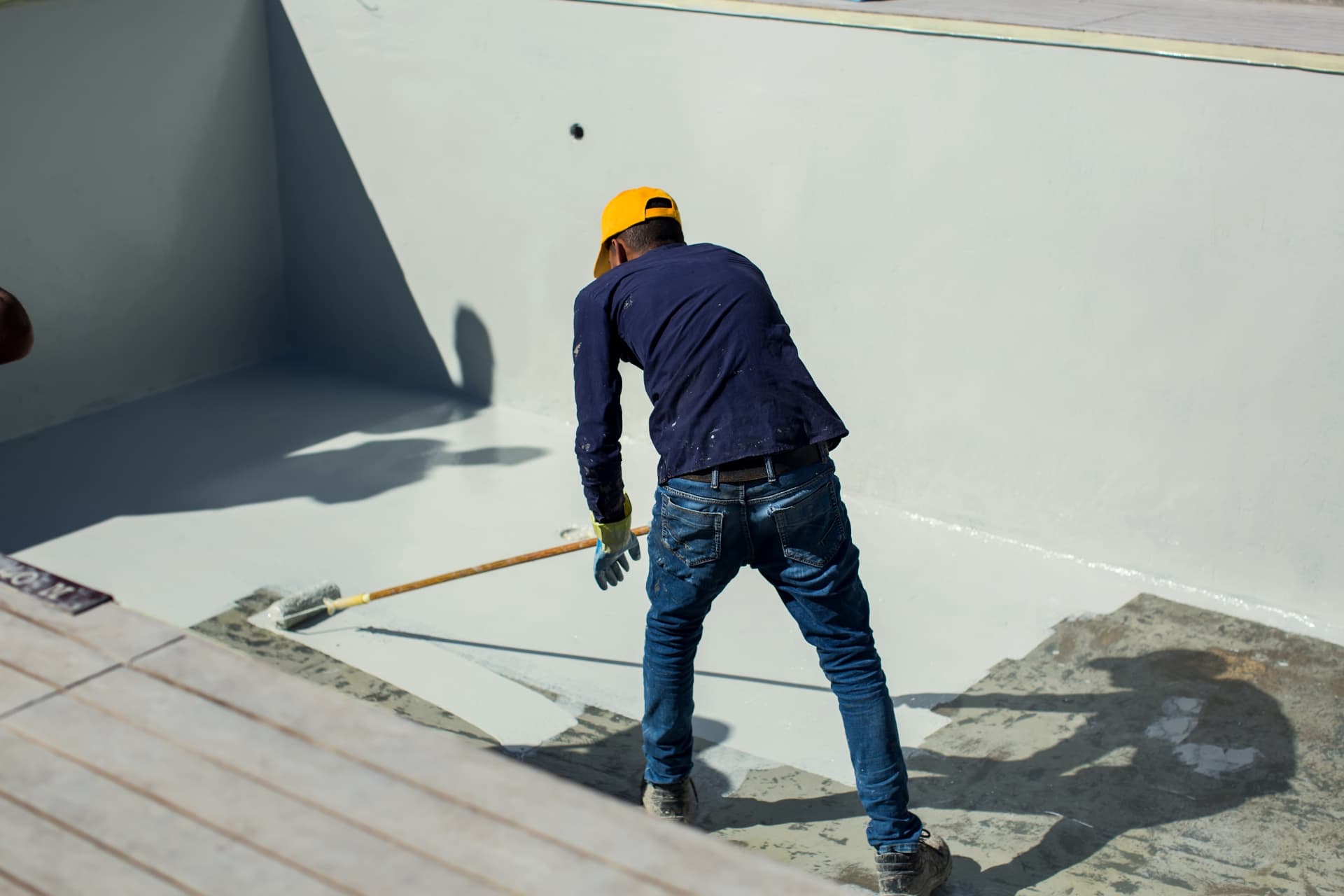 Painter rolling a protective coating across a rendered surface on a Central Coast job