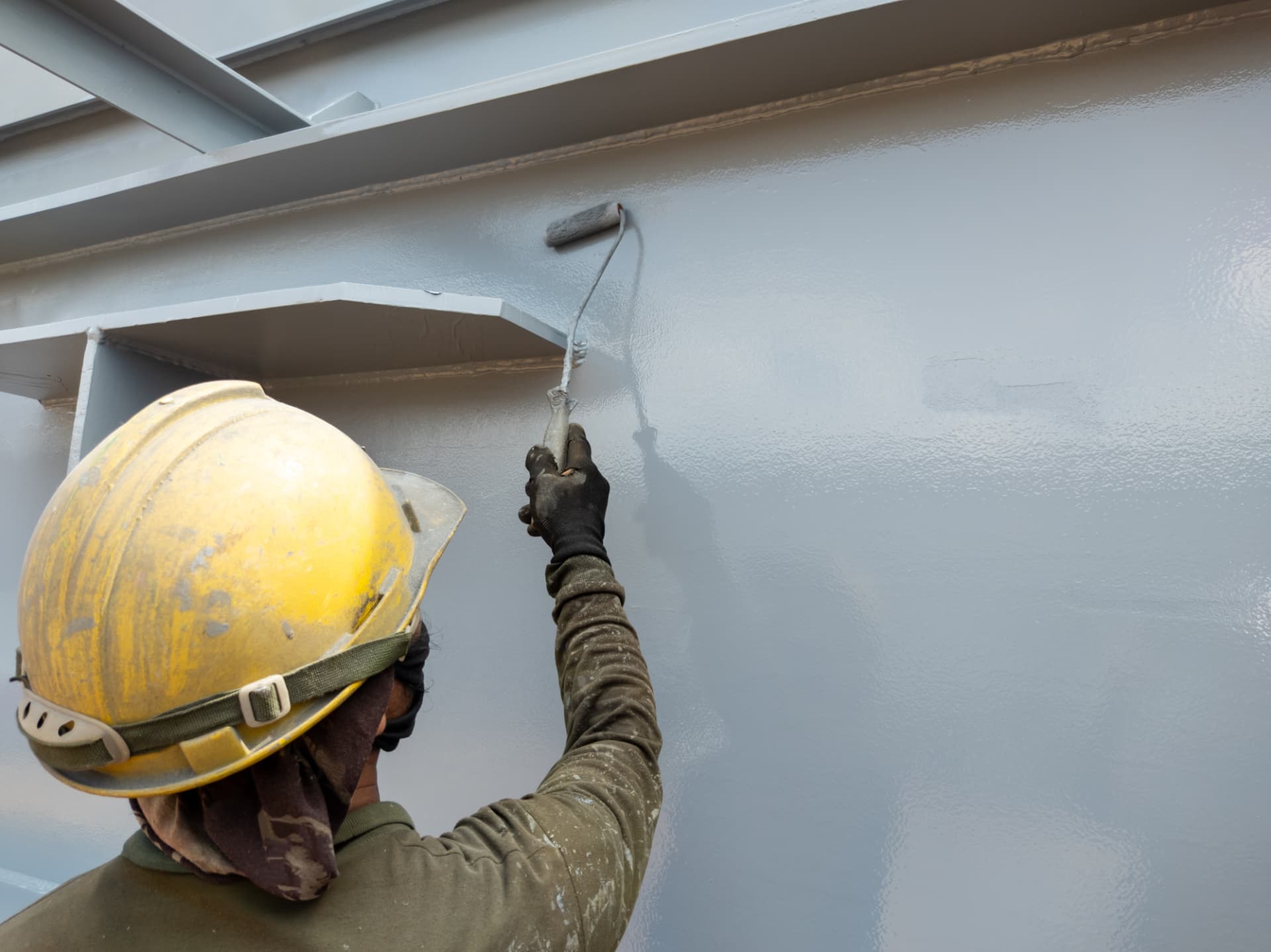 Painter rolling grey protective coating onto a steel wall on a Maitland commercial job