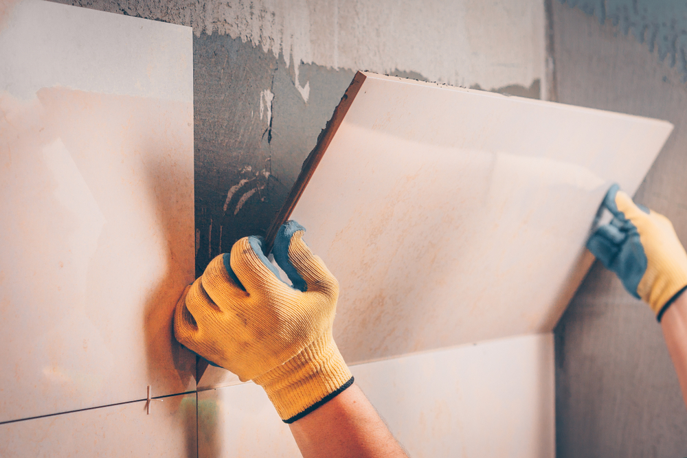 Decorator setting a large wall tile onto adhesive during an interior fit-out in Newcastle