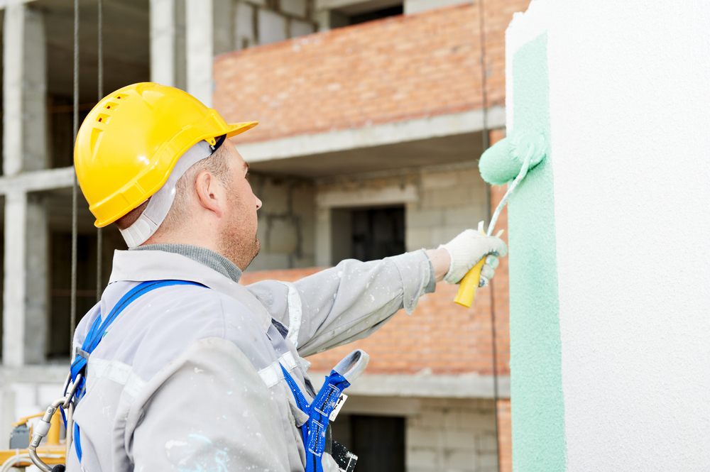Painter rolling render onto an exterior wall on a Hunter region building site