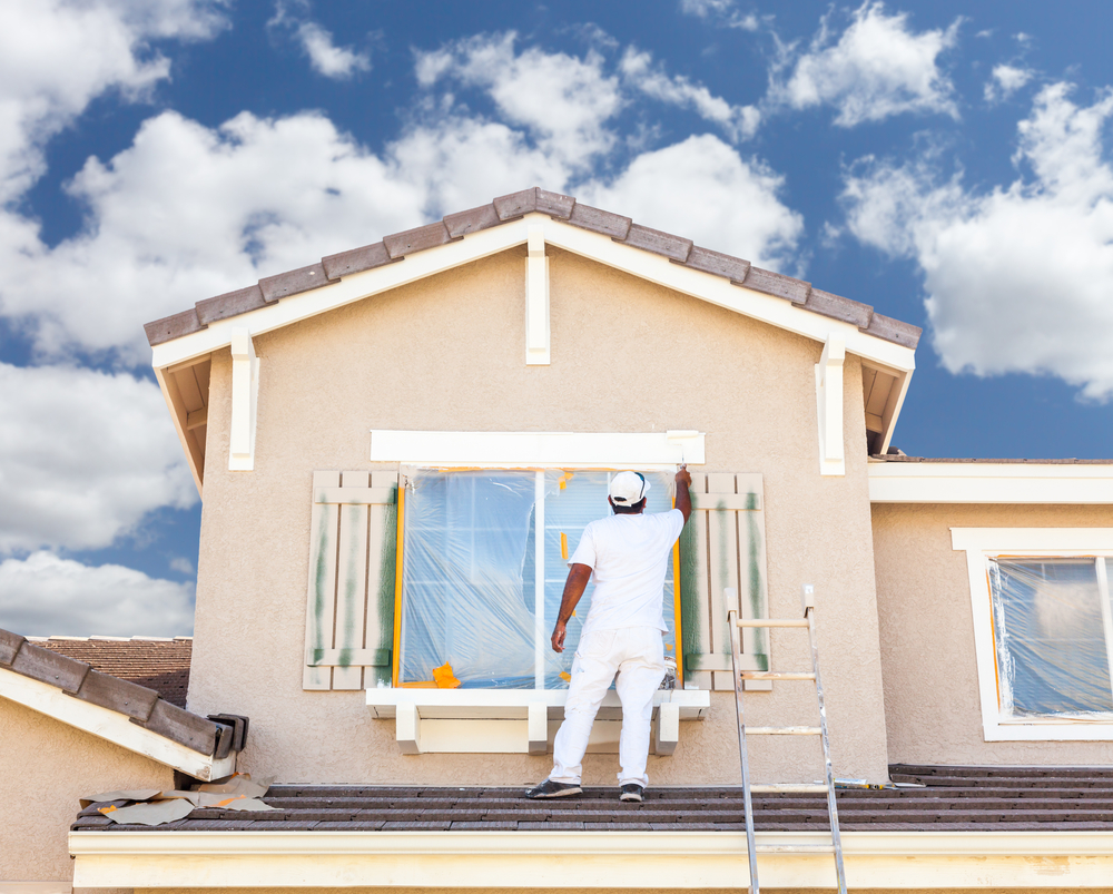 Painter cutting in window trim on a house exterior in the Hunter region