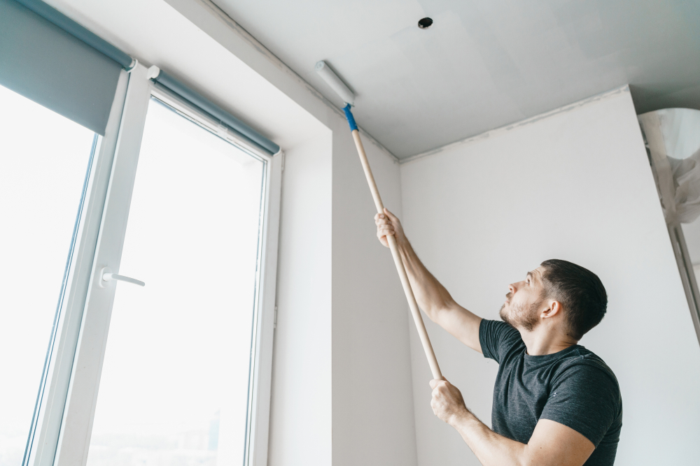 Painter rolling a freshly prepared ceiling with an extension roller during a Newcastle renovation