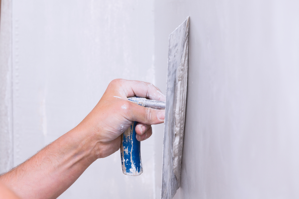 Plasterer smoothing wall filler with a trowel to prepare a Hunter Valley wall for painting