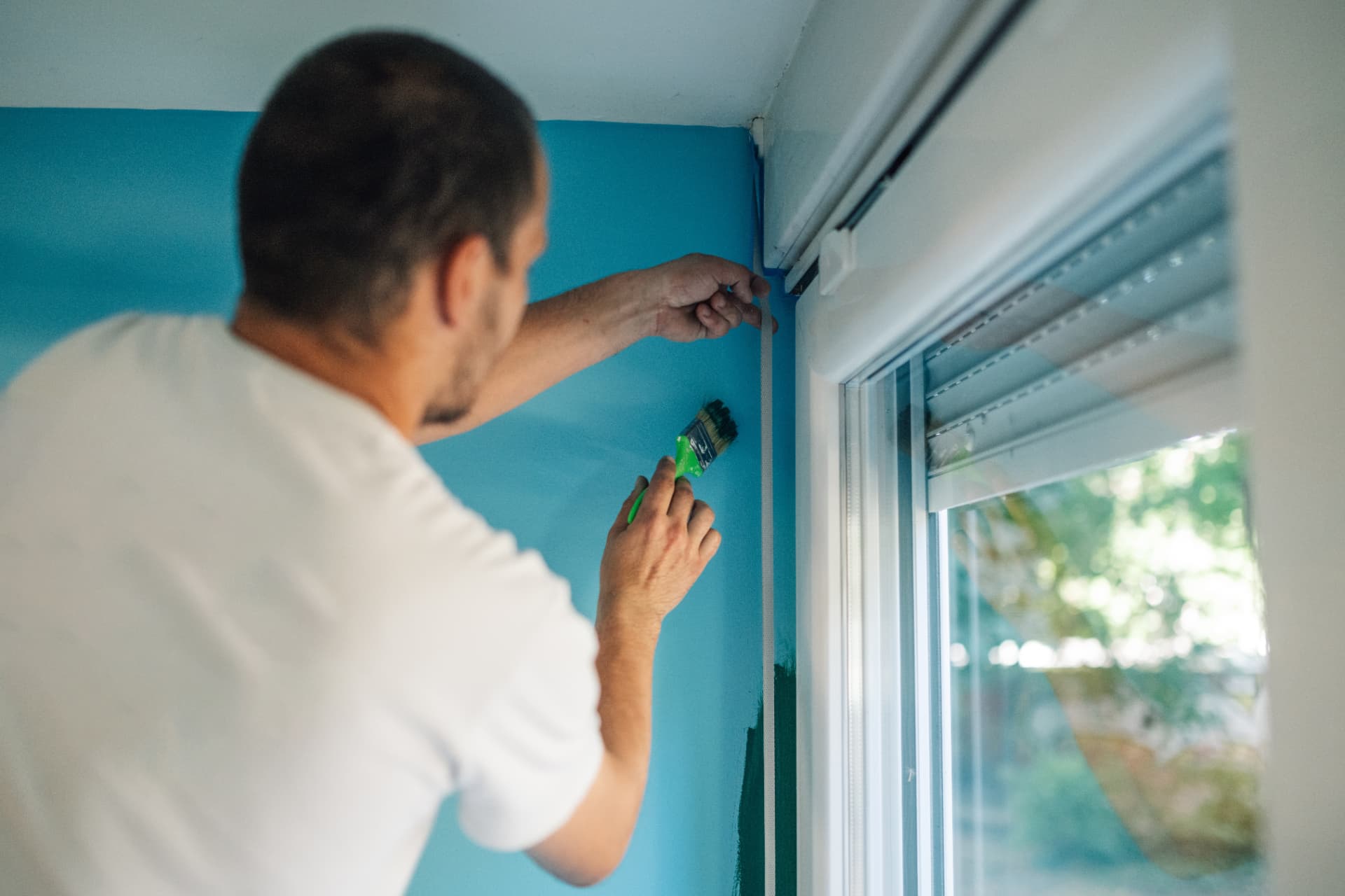 Painter cutting in paint beside a window reveal on an interior job in Port Stephens