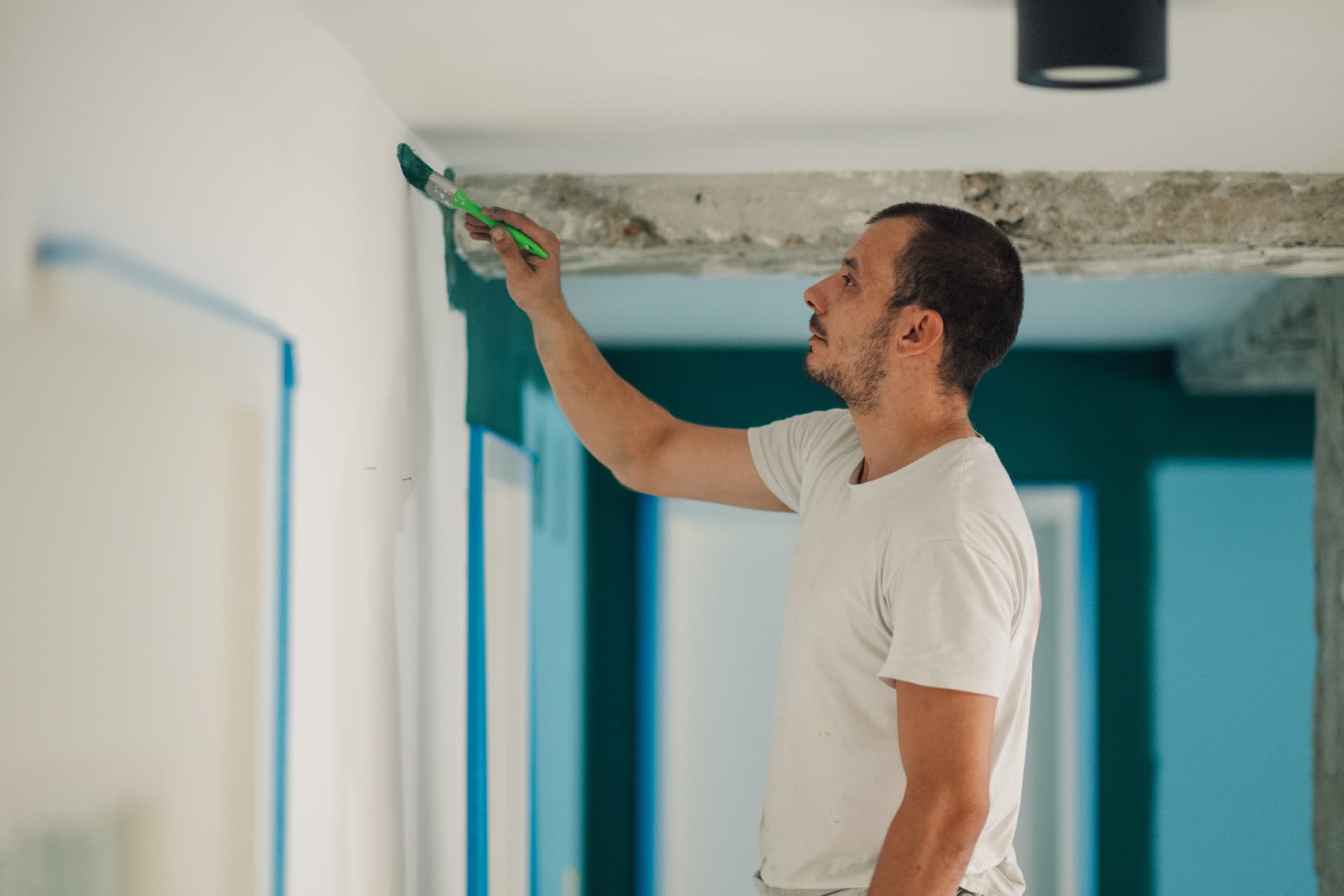 Painter cutting in a green wall edge beside a masked ceiling line in a Charlestown home
