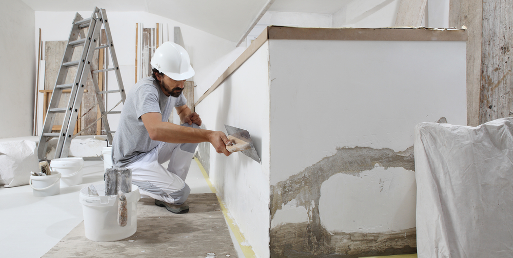 Plasterer trowelling patching compound onto a damaged wall before painting in Central Coast