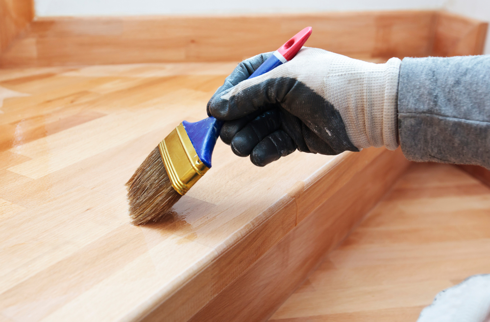 Painter brushing fresh varnish onto timber stair treads during a Port Stephens renovation