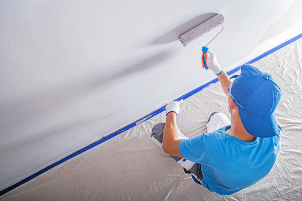 Painter rolling a fresh coat across a masked ceiling line on a Charlestown job