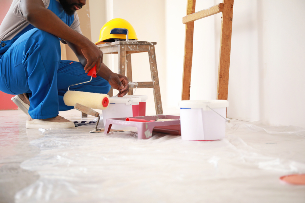 Painter preparing rollers and paint on a drop-sheeted floor in a Hunter region home