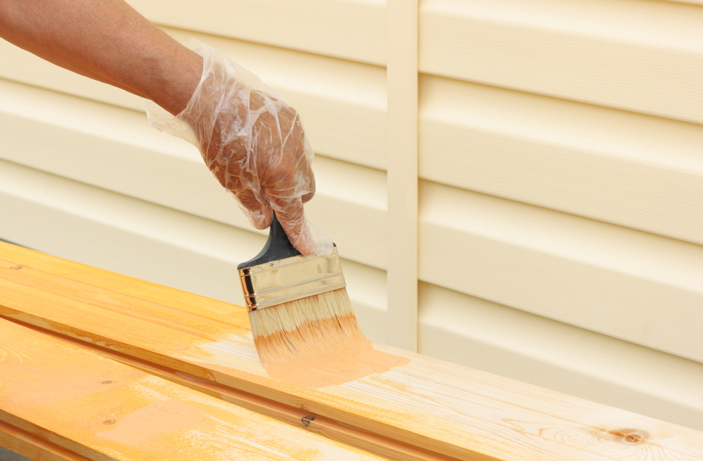 Painter brushing protective coating onto new timber during a Maitland renovation