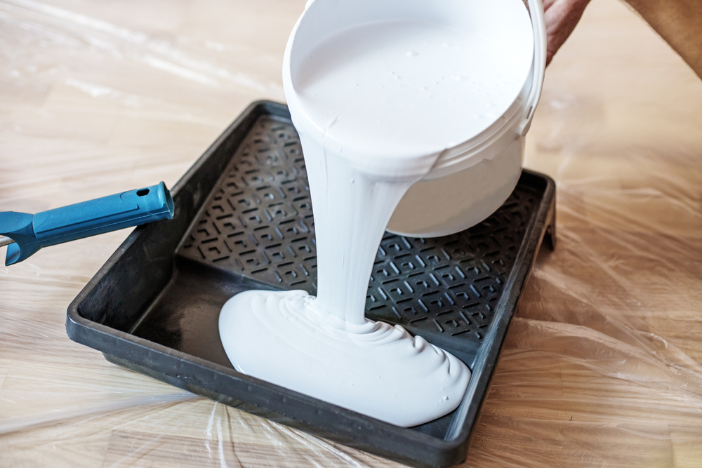 Paint being poured into a roller tray on a commercial painting job in Newcastle