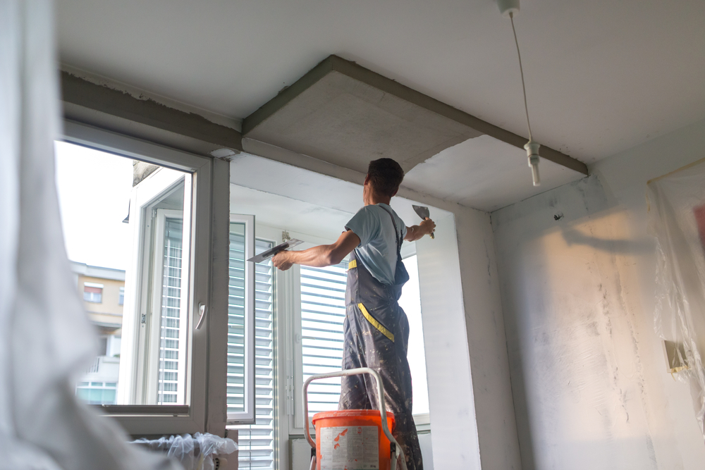 Painter smoothing filler across a ceiling bulkhead during a Cessnock home repaint