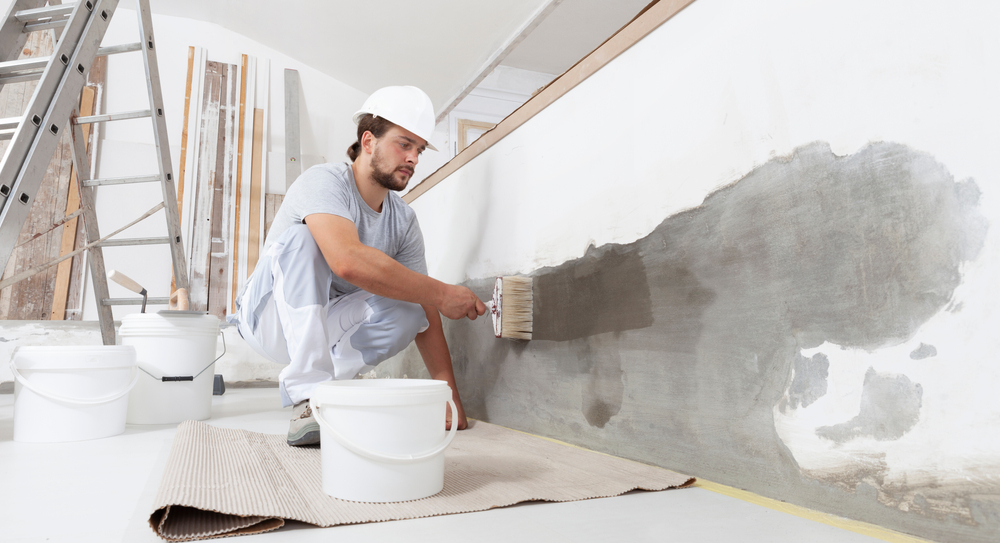 Painter brushing sealer onto a prepared interior wall in a Newcastle home