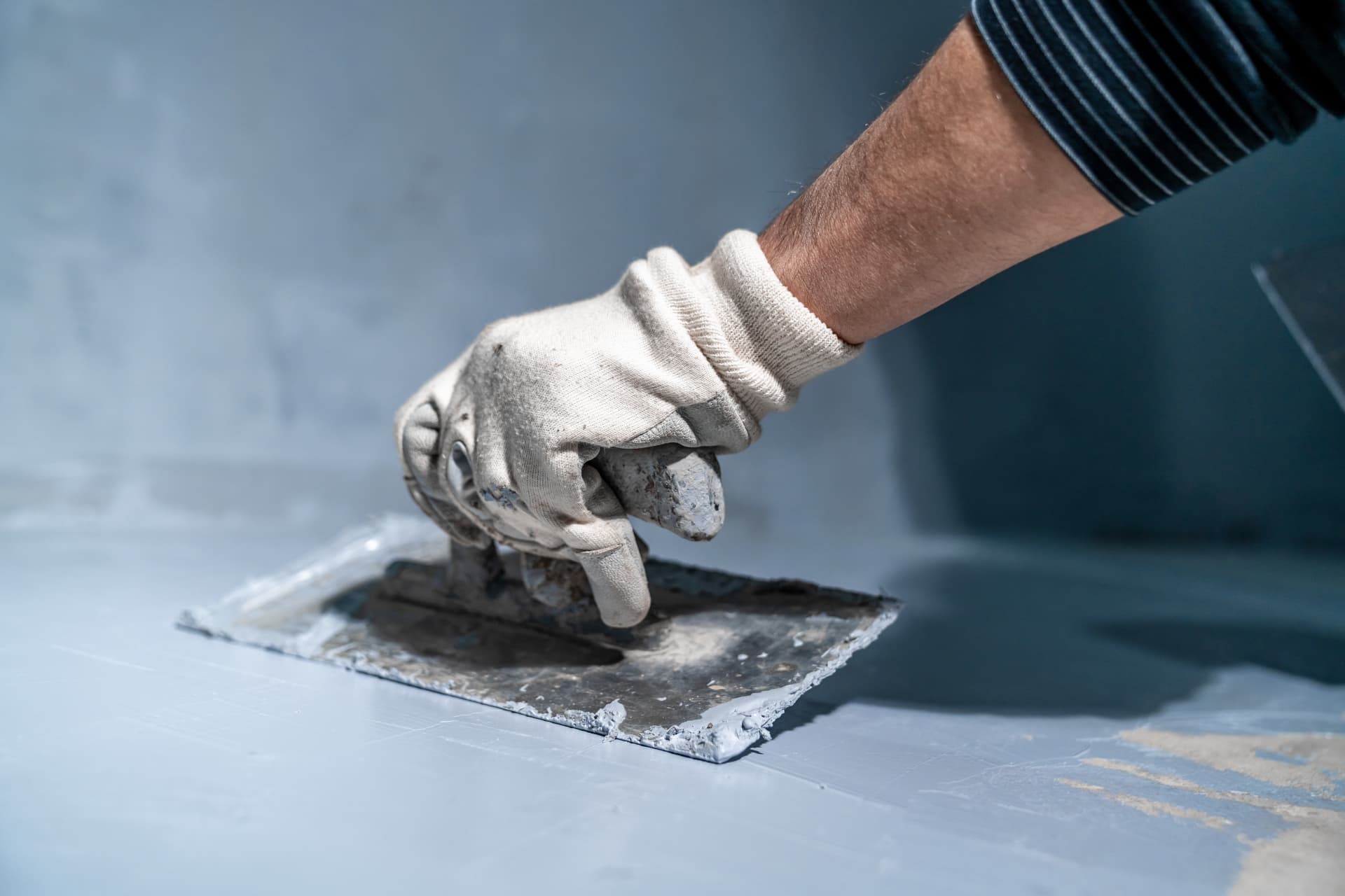 Plasterer smoothing filler with a trowel to prepare a Port Stephens wall for painting